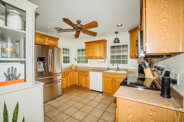 kitchen with crown molding, appliances with stainless steel finishes, a sink, light tile patterned floors, and light countertops