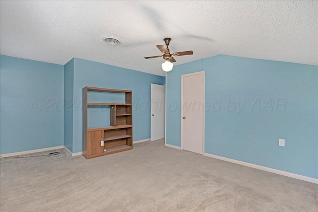 unfurnished bedroom with vaulted ceiling, carpet flooring, a textured ceiling, and visible vents