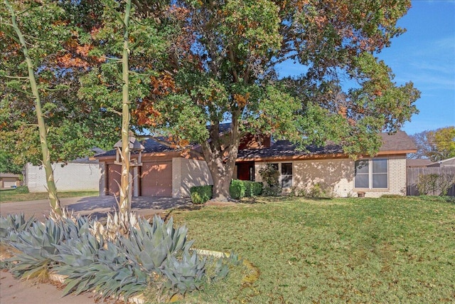 single story home featuring fence, a front yard, brick siding, an attached garage, and driveway