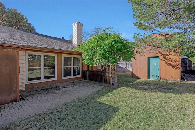 view of yard with fence, a storage unit, an outbuilding, and a patio area