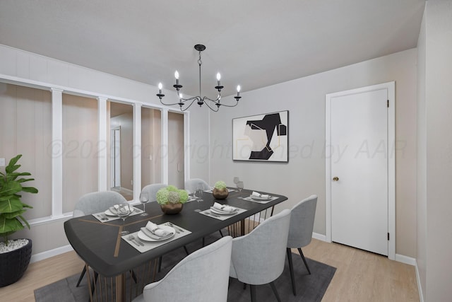 dining space featuring baseboards, light wood-style flooring, and a notable chandelier