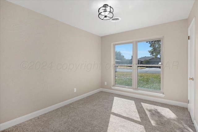 carpeted empty room featuring baseboards and visible vents