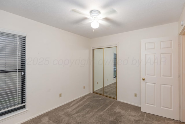 unfurnished bedroom with carpet flooring, a closet, baseboards, and ceiling fan