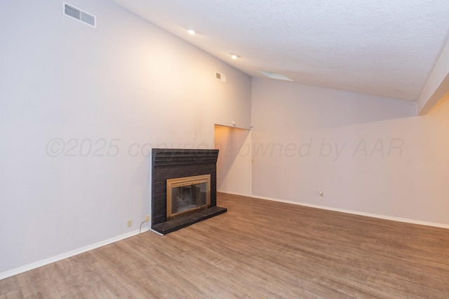 unfurnished living room with lofted ceiling, wood finished floors, a glass covered fireplace, and baseboards