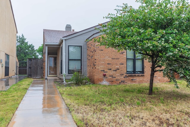 view of front of home featuring a chimney, brick siding, driveway, and a shingled roof