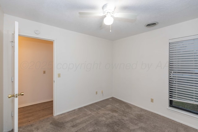 carpeted empty room with a ceiling fan and baseboards