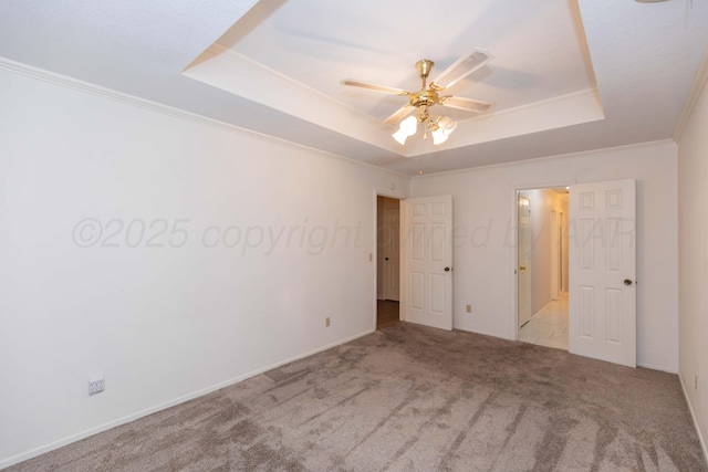 unfurnished bedroom with a tray ceiling, carpet floors, crown molding, and ceiling fan