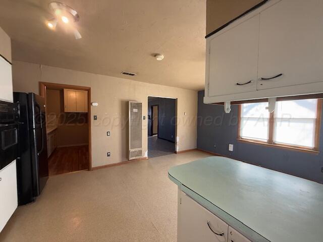 kitchen featuring black fridge and white cabinets