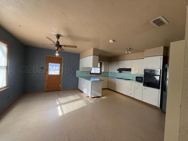 kitchen with kitchen peninsula, white cabinets, ceiling fan, and black appliances