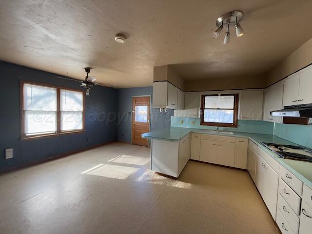 kitchen with white cabinetry, sink, kitchen peninsula, and stainless steel gas stovetop