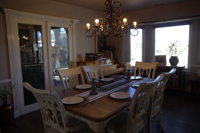 dining space with dark wood-type flooring and an inviting chandelier