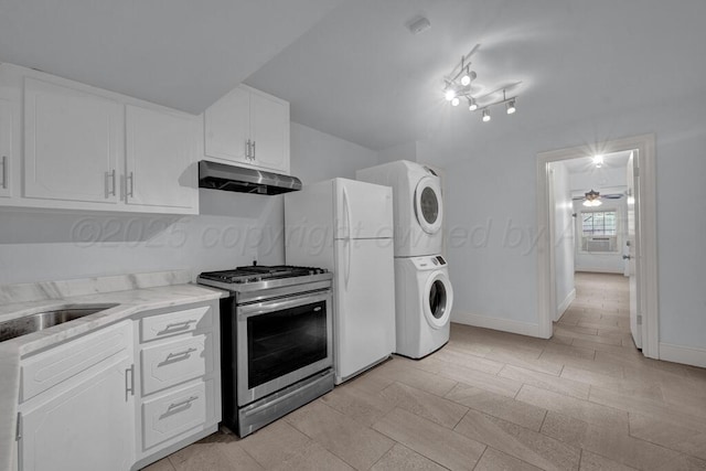 2411 S Lipscomb St, Amarillo, TX 79109 - kitchen with under cabinet range hood, estacked washer and dryer, stainless steel range with gas cooktop, white cabinets, and a ceiling fan