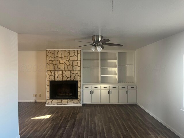 1902 Rogers St, Amarillo, TX 79106 - unfurnished living room featuring baseboards, dark wood finished floors, a ceiling fan, and a stone fireplace
