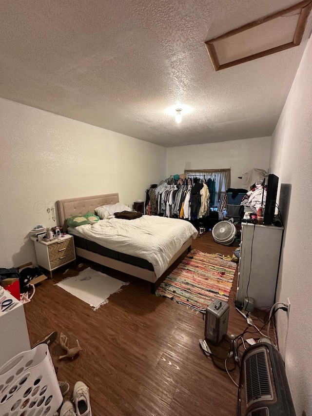 bedroom featuring a textured ceiling, wood finished floors, and attic access