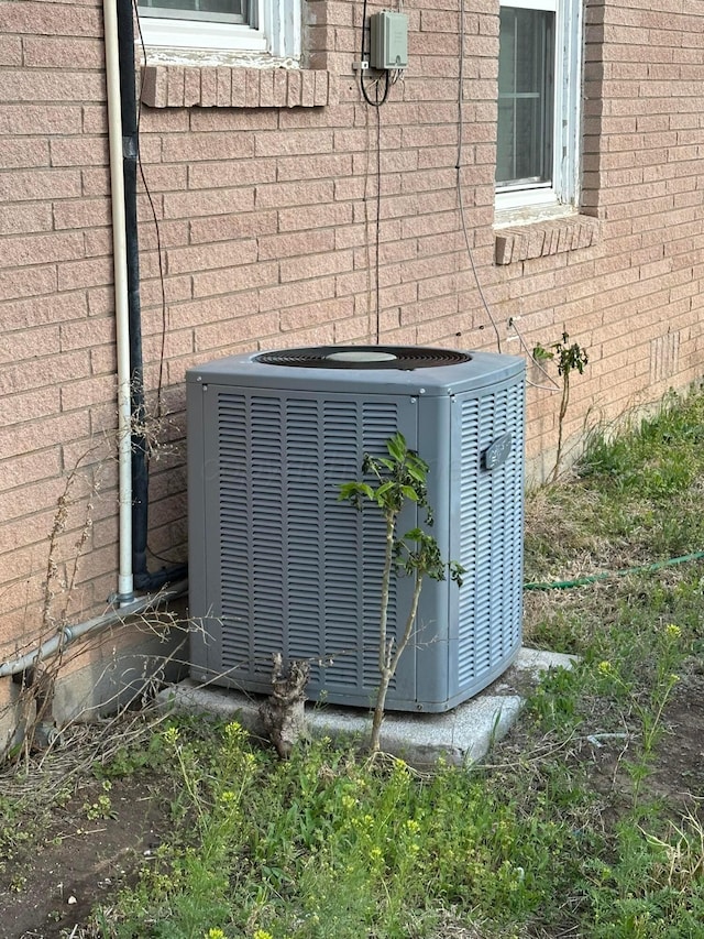 exterior details featuring cooling unit and brick siding