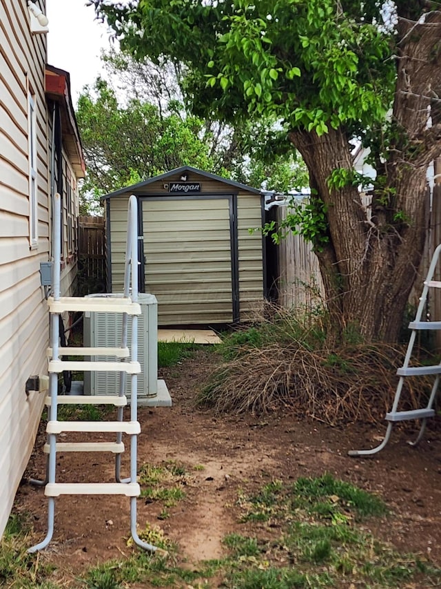 view of yard featuring fence, central AC unit, a shed, and an outbuilding
