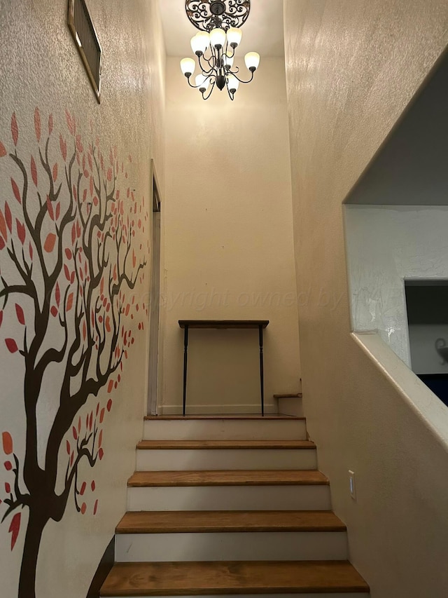 staircase with an inviting chandelier and visible vents
