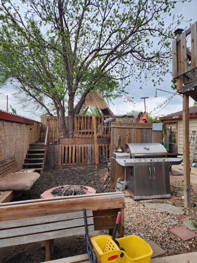 view of patio with stairway, fence, a fire pit, and a grill