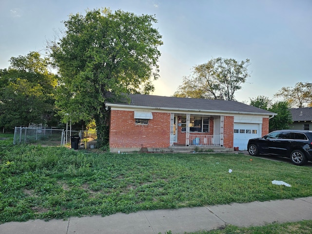 ranch-style home with a garage, a lawn, and covered porch