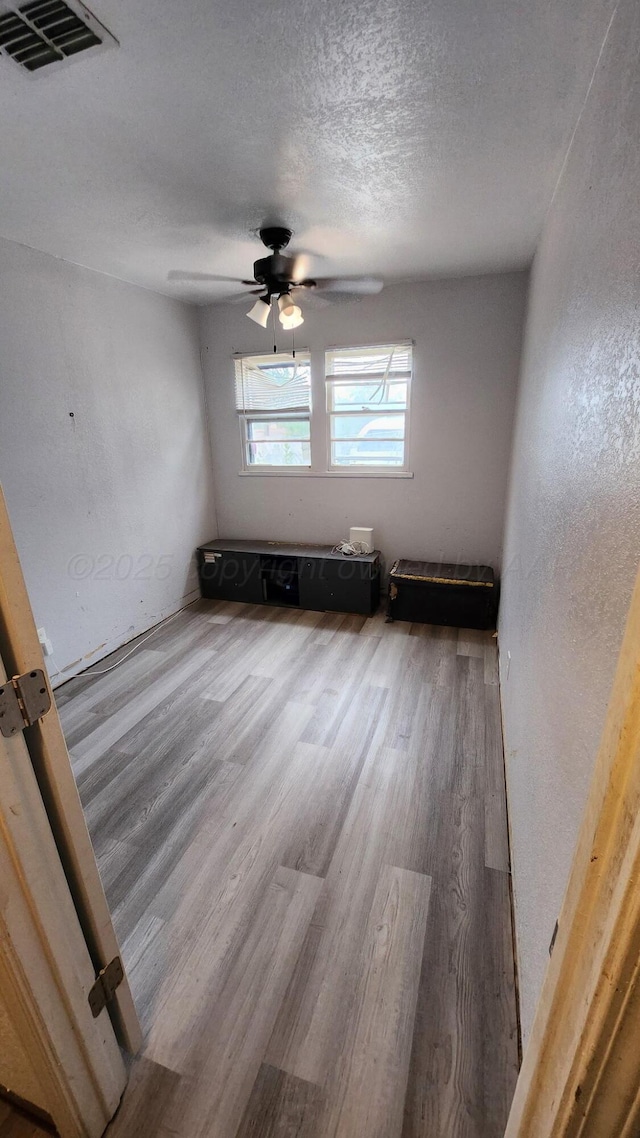 2738 Palm St, Amarillo, TX 79107 - spare room featuring wood finished floors, a ceiling fan, a textured ceiling, and a textured wall