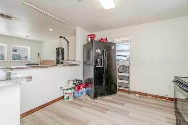 2738 Palm St, Amarillo, TX 79107 - kitchen with black fridge, range with electric stovetop, light wood-style flooring, and a textured ceiling