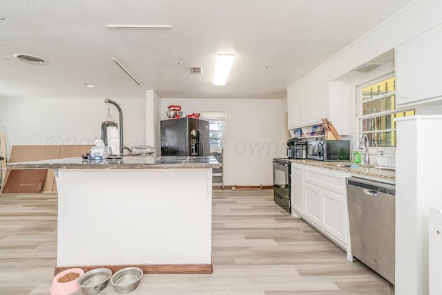 2738 Palm St, Amarillo, TX 79107 - kitchen featuring appliances with stainless steel finishes, light wood finished floors, white cabinets, and a kitchen island with sink