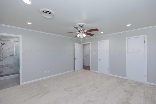 unfurnished bedroom with crown molding, ensuite bath, light carpet, two closets, and ceiling fan