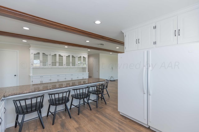 kitchen featuring white cabinets, a kitchen bar, dark hardwood / wood-style floors, and white refrigerator