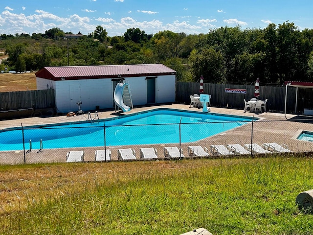 view of swimming pool with an outbuilding, a patio, and a water slide