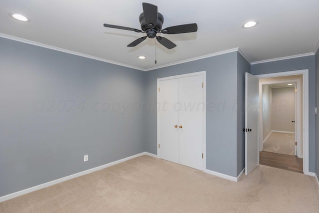 unfurnished bedroom featuring ornamental molding, light carpet, ceiling fan, and a closet