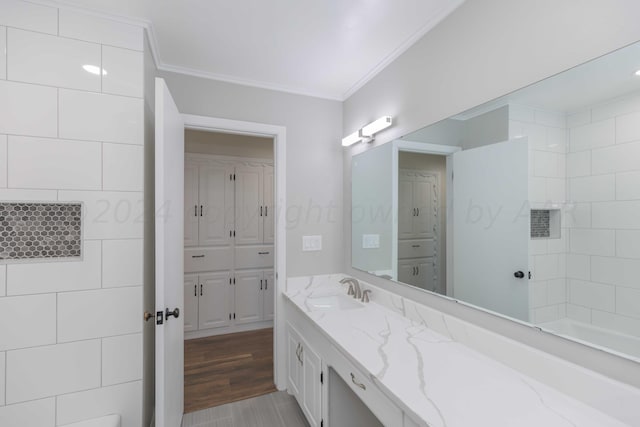 bathroom featuring wood-type flooring, vanity, and ornamental molding