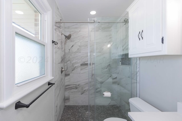 bathroom featuring a shower with shower door and toilet