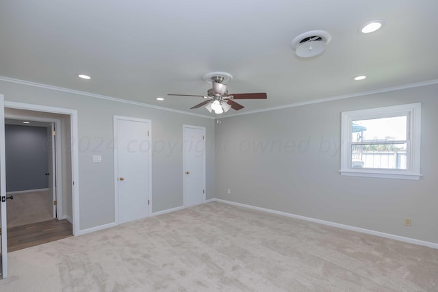 unfurnished bedroom with multiple closets, light colored carpet, ceiling fan, and crown molding