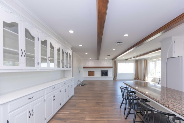 kitchen featuring white cabinets, dark wood-type flooring, crown molding, and dark stone countertops