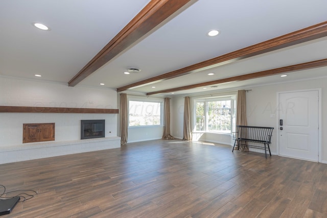 unfurnished living room featuring beamed ceiling and dark hardwood / wood-style floors