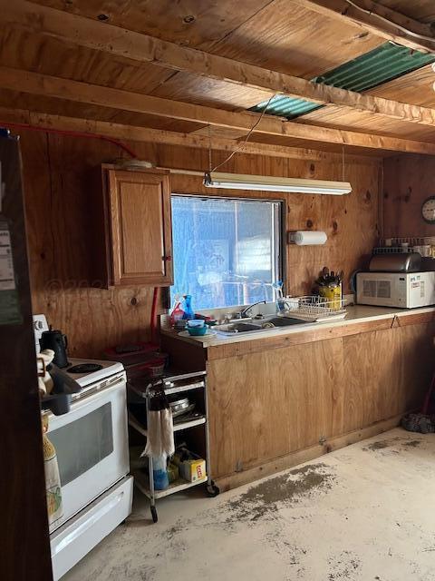 kitchen featuring sink, wood ceiling, white range with electric stovetop, and wood walls