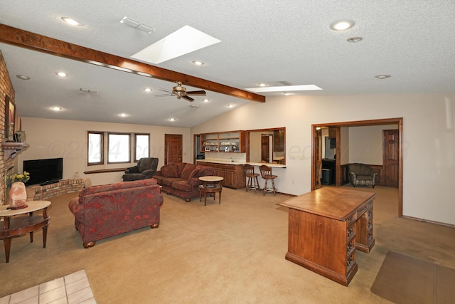 living room with light carpet, vaulted ceiling with skylight, ceiling fan, a textured ceiling, and a fireplace