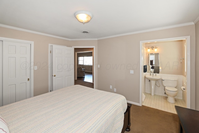bedroom with ensuite bathroom, dark tile patterned flooring, and crown molding
