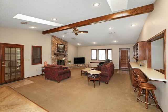 carpeted living room with a textured ceiling, ceiling fan, lofted ceiling with skylight, and a fireplace