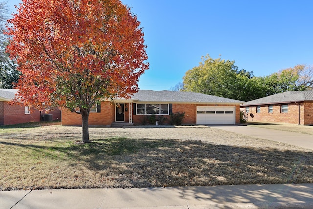 view of front of home featuring a front yard, central AC unit, and a garage