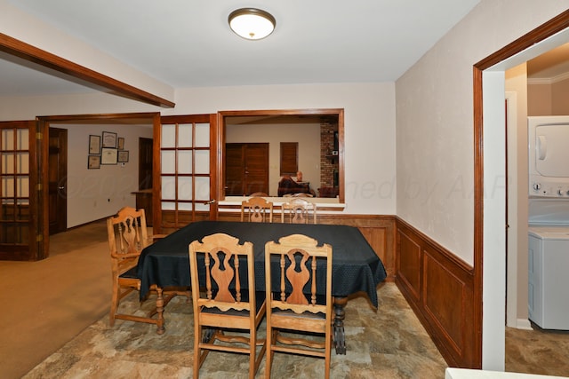 dining area featuring stacked washer / drying machine, carpet floors, wooden walls, and french doors