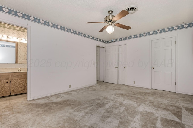 unfurnished bedroom with carpet, connected bathroom, baseboards, a ceiling fan, and a sink