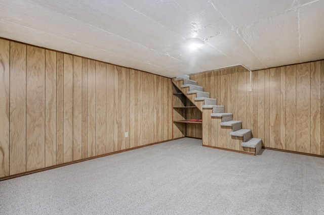 finished basement featuring wooden walls, carpet flooring, stairway, and baseboards
