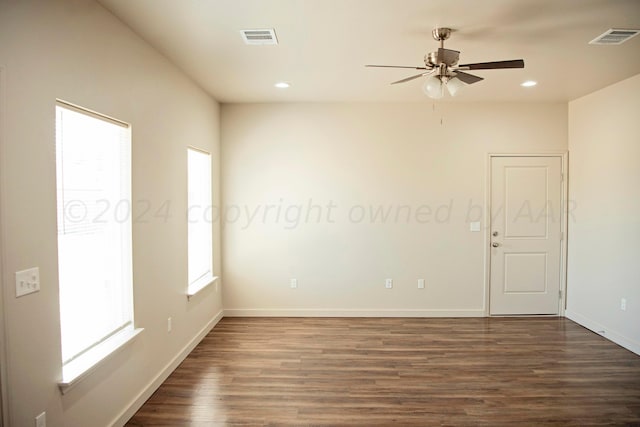 empty room featuring dark wood-type flooring, ceiling fan, and a healthy amount of sunlight