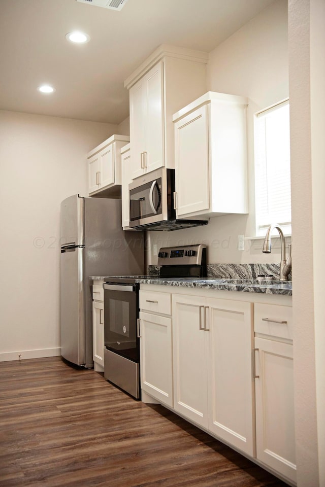 kitchen with white cabinetry, sink, light stone counters, appliances with stainless steel finishes, and dark hardwood / wood-style floors