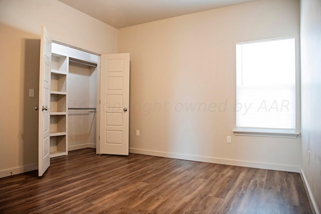 unfurnished bedroom with a closet and dark hardwood / wood-style flooring