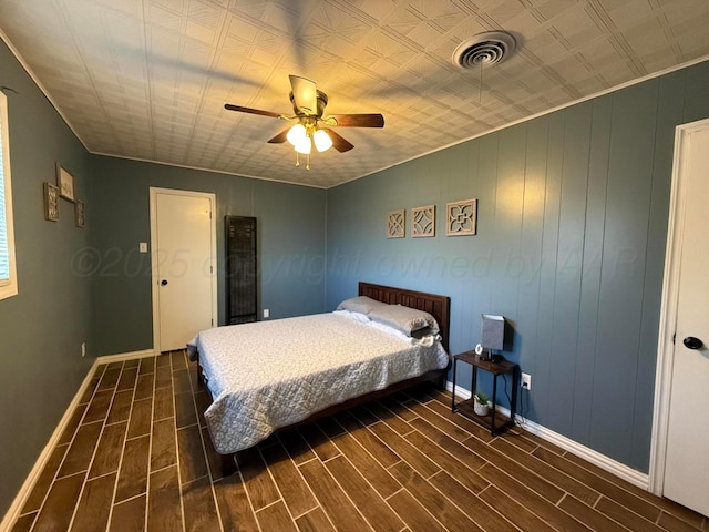 bedroom with baseboards, visible vents, a ceiling fan, and wood finish floors