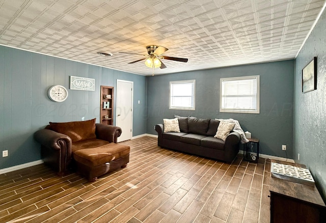 living room with a ceiling fan, baseboards, and wood finished floors