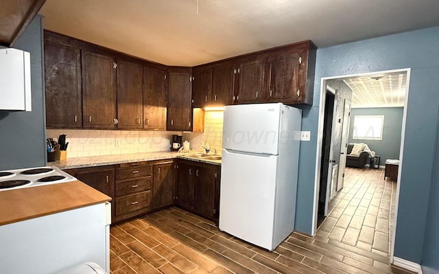 kitchen with dark brown cabinets, tasteful backsplash, light countertops, and freestanding refrigerator