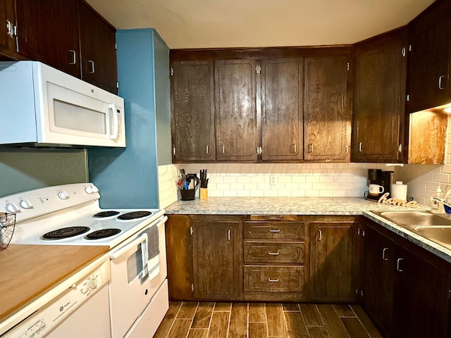 kitchen with wood finish floors, light countertops, backsplash, a sink, and white appliances